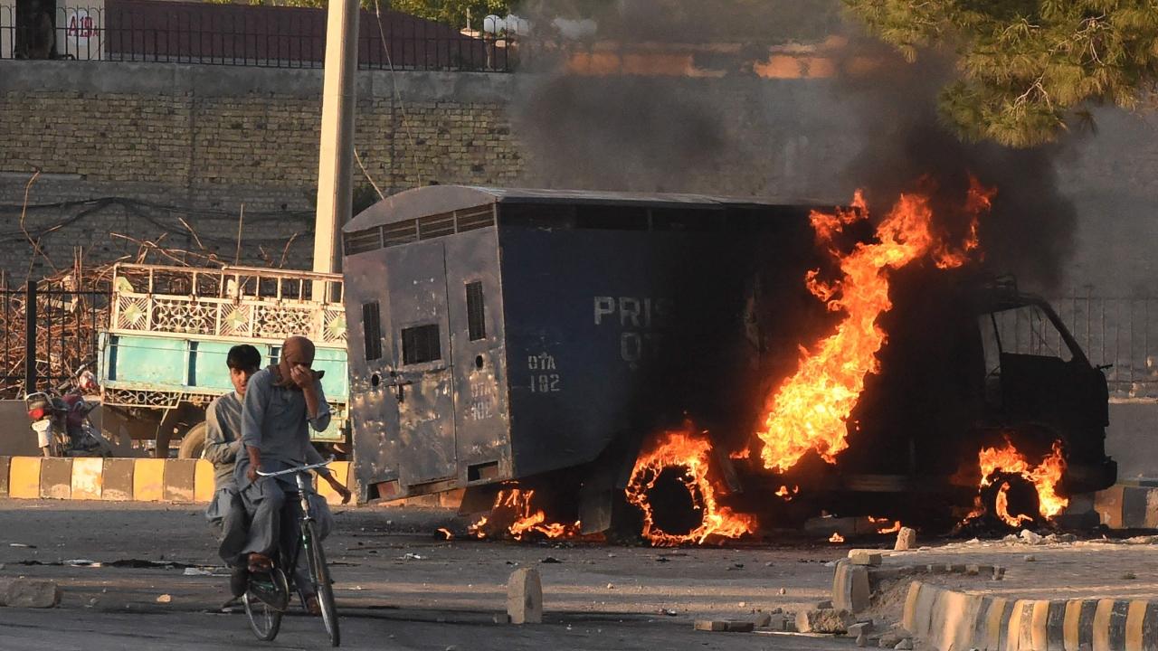 Men on a bike ride past a burning police vehicle during a protest by Pakistan Tehreek-e-Insaf party activists and supporters of former Pakistan's Prime Minister Imran against the arrest of their leader, in Quetta on May 9. Police fired water cannon and tear gas on May 9 to quell protests that erupted in several cities across Pakistan, hours after former prime minister Imran Khan was arrested in connection with a graft case