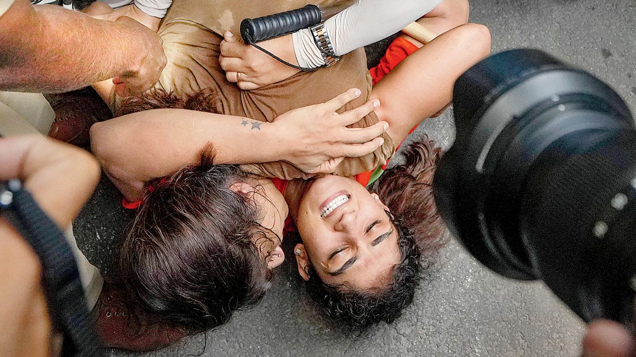 Security personnel pin down wrestlers Vinesh Phogat and Sangeeta Phogat before detaining them, during wrestlers’ protest march towards new Parliament building, in New Delhi, on Sunday