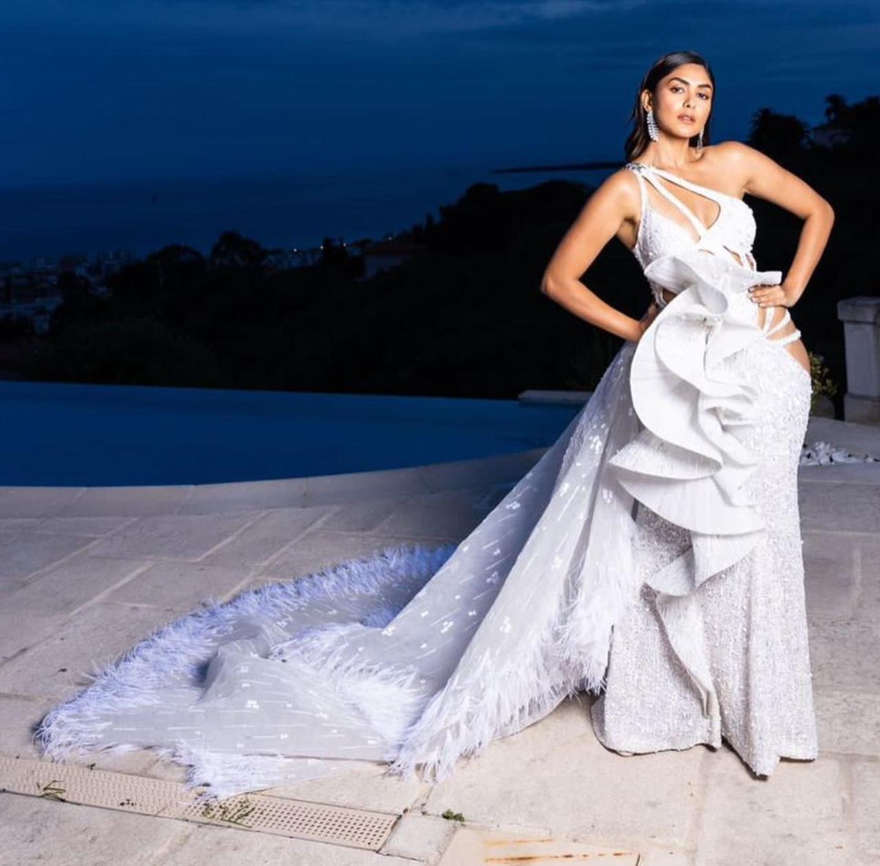 The 'Sita Ramam' star stole the spotlight as she stepped out in a bespoke white cutout gown by Falguni and Shane Peacock on day 3 of the Cannes Film Festival. The dramatic long trail with feather detailing and the beautiful cutouts on the waist were the key takeaways of Mrunal's mesmerising white ensemble. Mrunal exuded maximum charm and elegance as she stuck beautiful poses on the red carpet for photogs in her spotless shimmery gown. 