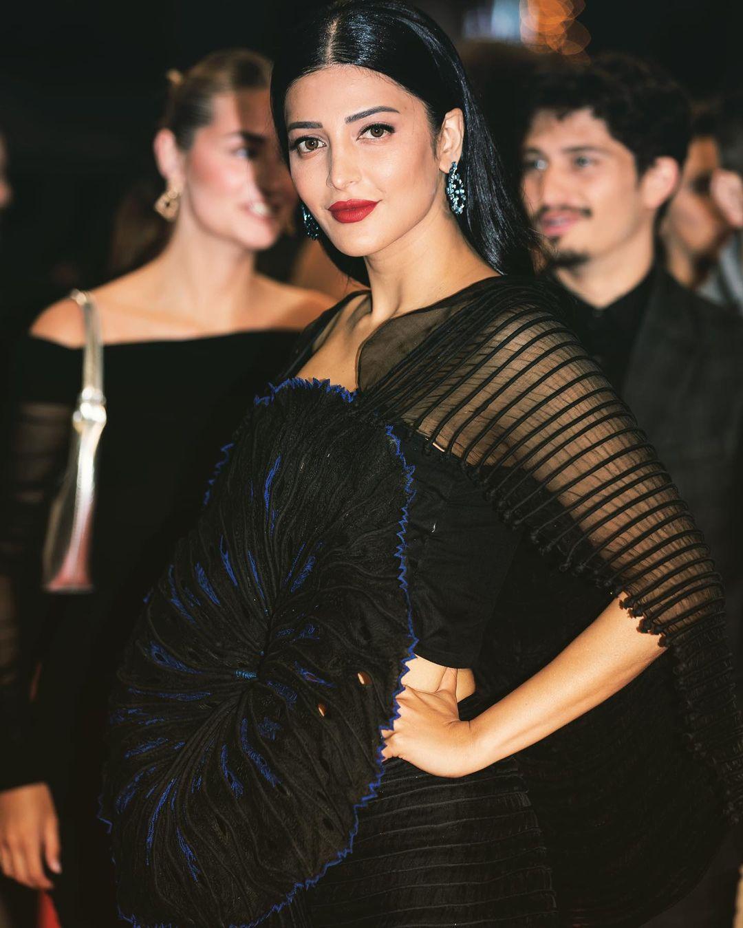 Shruti Haasan who is attending the coveted Cannes Film Festival for the second time, painted the red carpet black as made a stylish appearance in a beautiful black sheer dress which featured a chunky floral pattern on the front with hints of blue. 