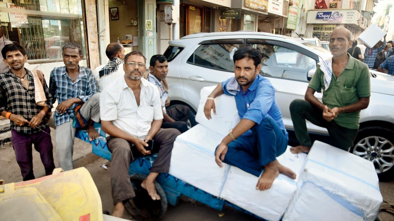 Hand-cart puller Omprakash Yadav (third from left) parks his cart on the roadside, if and when the heat gets too intense. Pic/Sameer Markande
