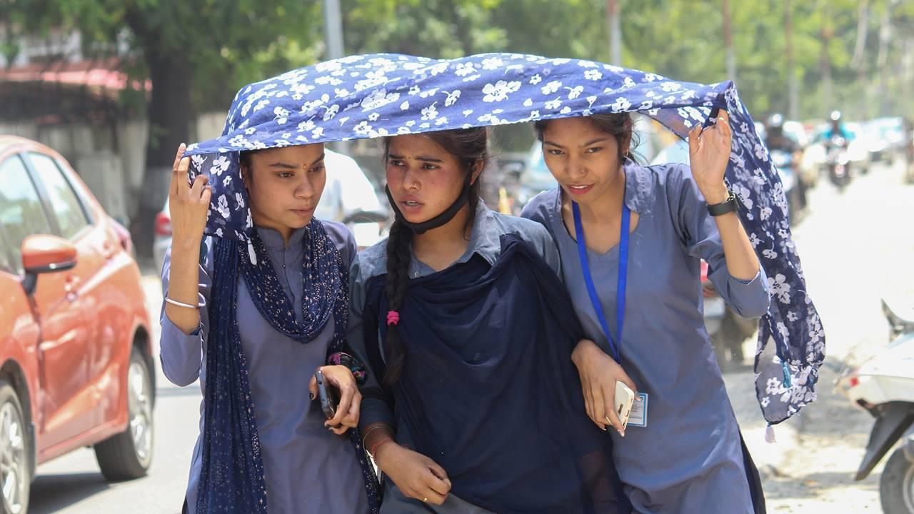 Students covering themselves with a scarf walk on a road on a hot summer day, in Dehradun, Saturday, May 20, 2023. Pic/PTI