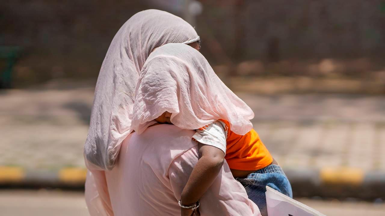 A woman covers herself and a child with a scarf during a hot summer afternoon, in New Delhi, Friday, May 19, 2023. Pic/PTI
