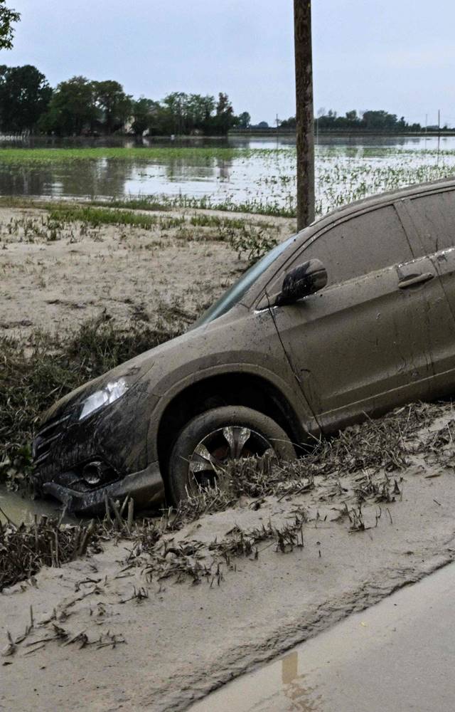 A car wich was washed away by muddy waters is pictured in a ditch on May 20, 2023 near the village of Coccolia, Ravenna, after floodwaters hit Italy.