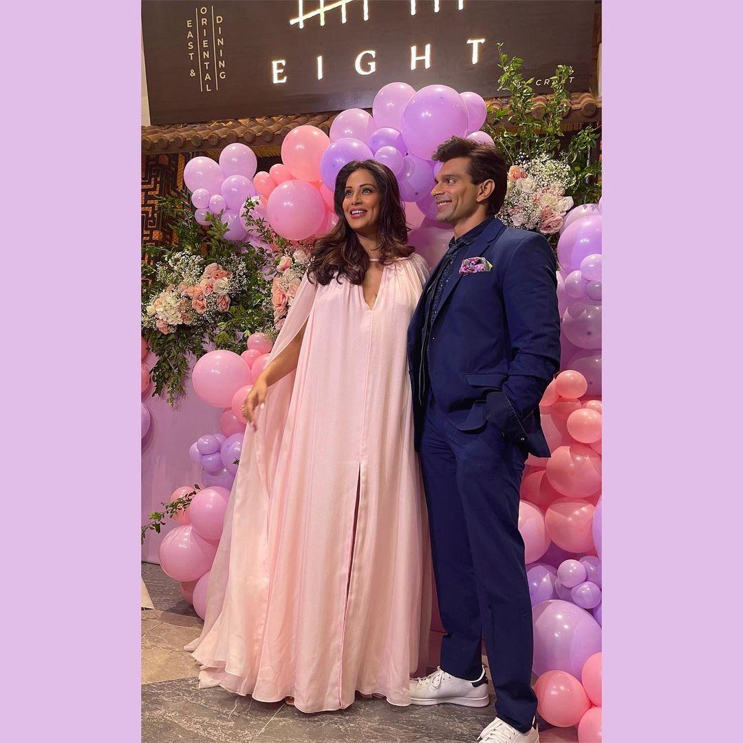 At her baby shower, Bipasha Basu dressed in a pastel pink gown, with a plunging neckline and thigh high slit. The gown had a silk cape and she completed the look with dangling earrings, rings, and a bracelet.