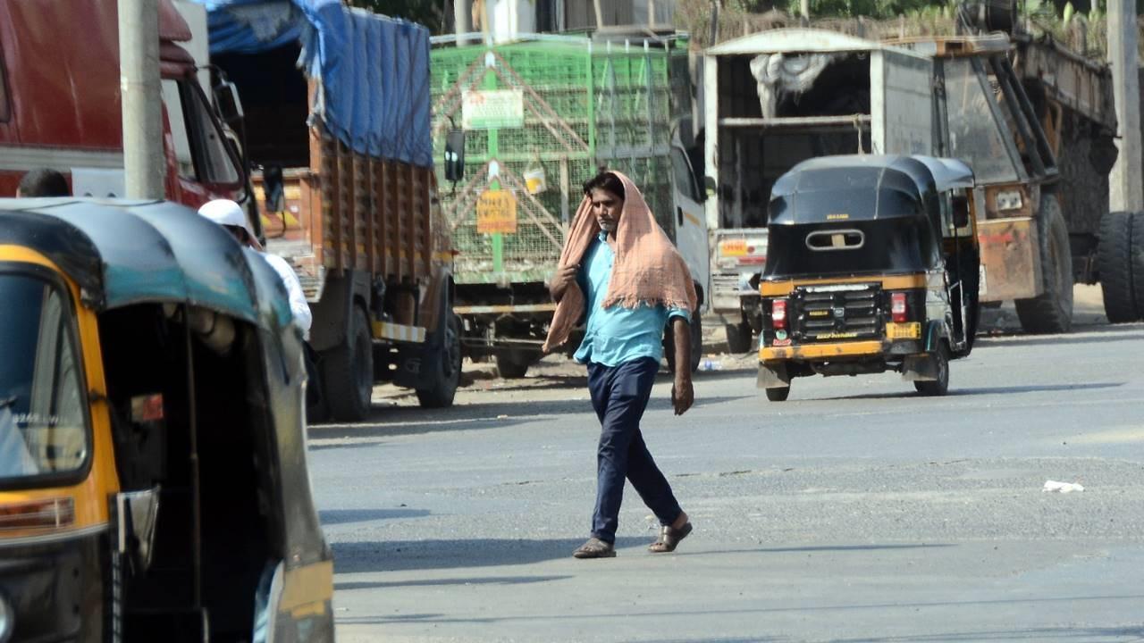 A man crosses a road in the city amid scorching sunlight.