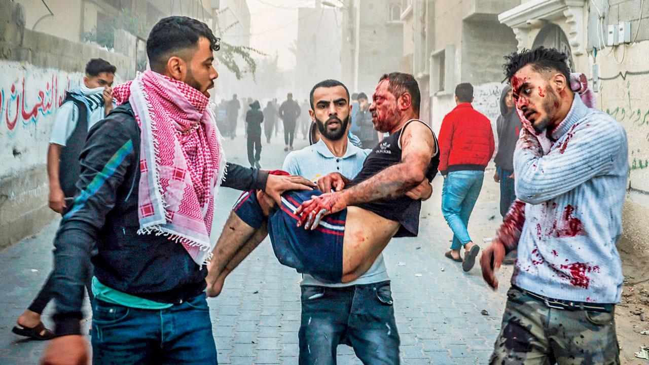 A Palestinian man carries an injured man as people flee following an Israeli strike in Rafah