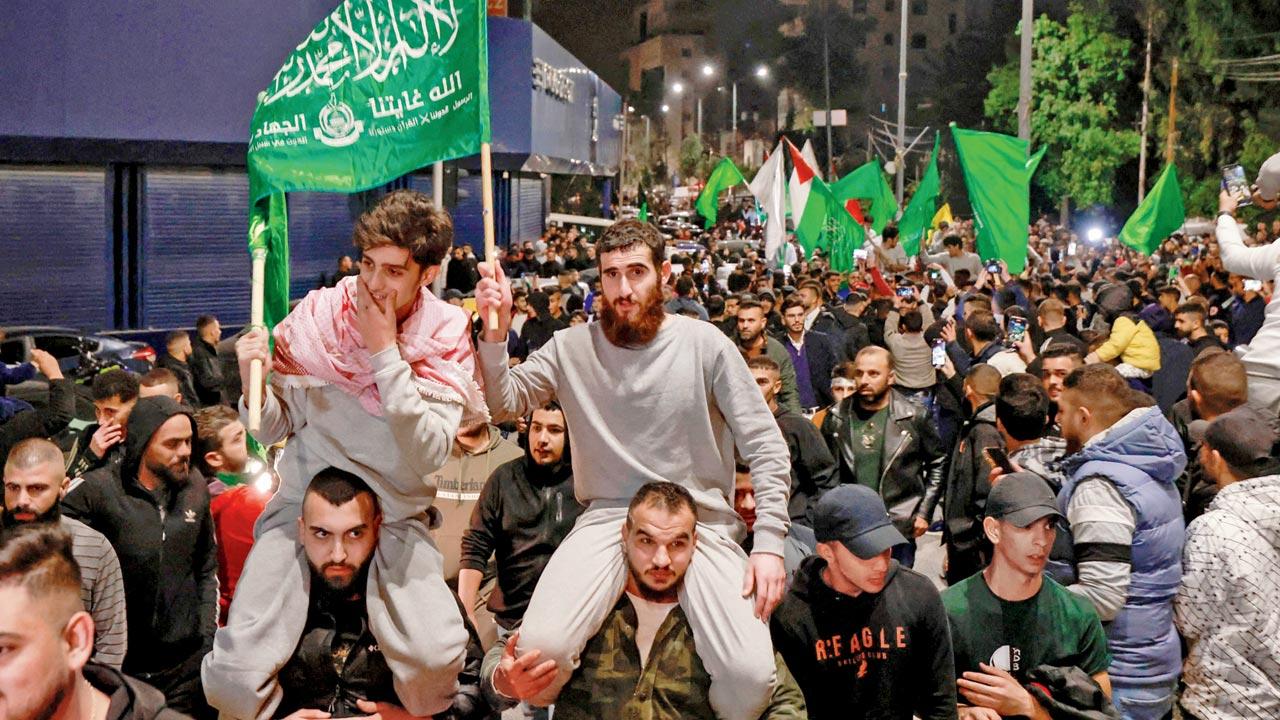 Palestinians prisoners (wearing grey jumpers) cheer after being released. Pic/AP