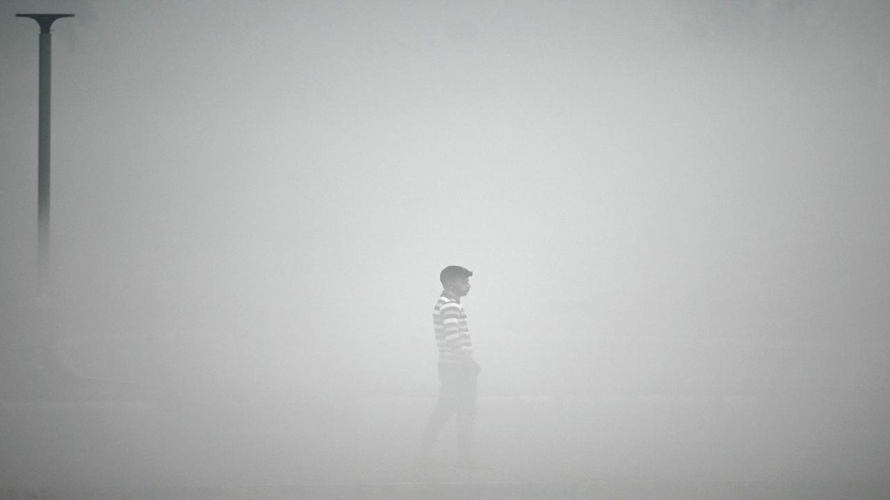 A pedestrian walks along the roadside amid heavy smoggy conditions in New Delhi on November 13, 2023. Pic/AFP