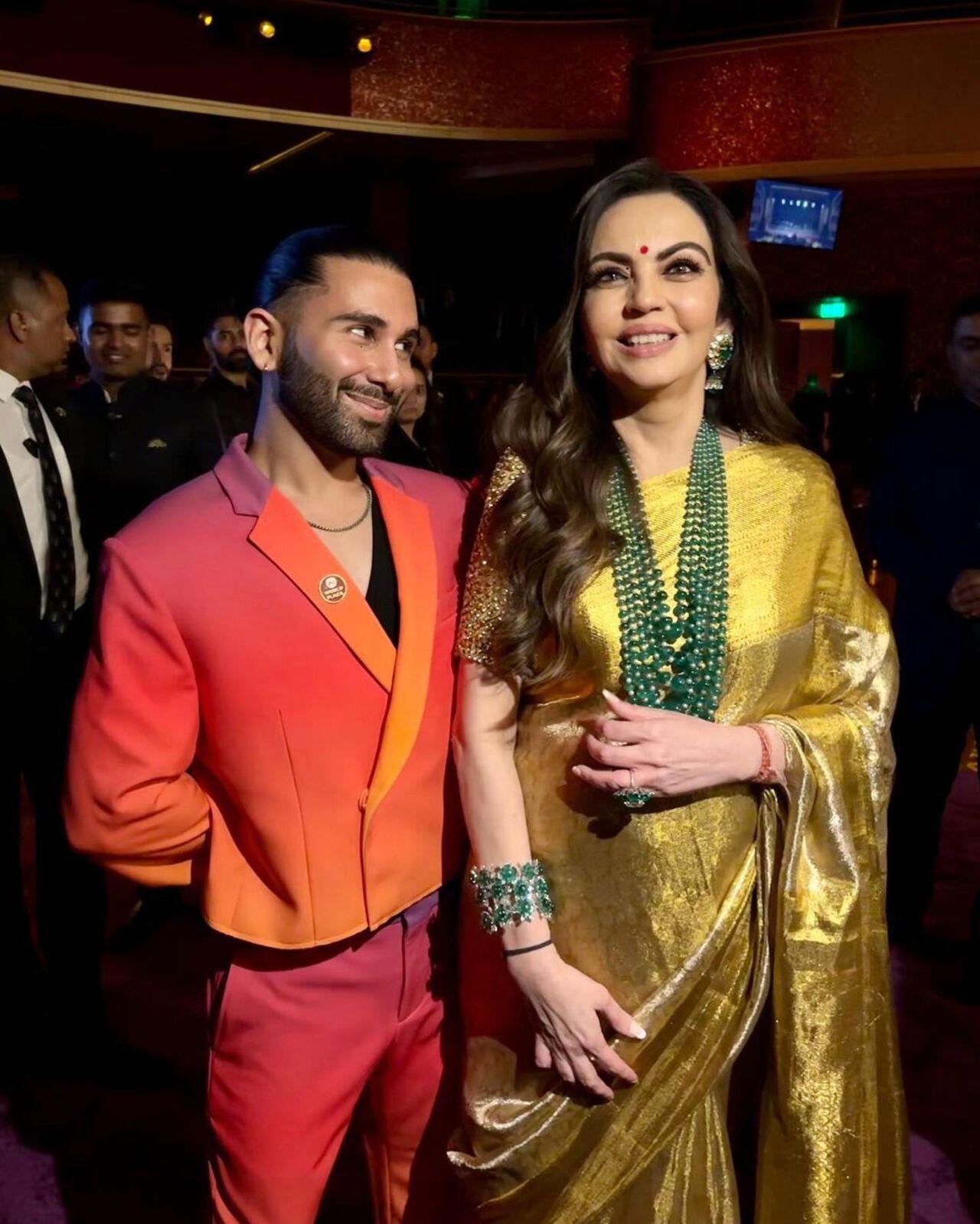 Orry sparkles in a suit with all shades of red and poses beside the beautiful Nita Ambani