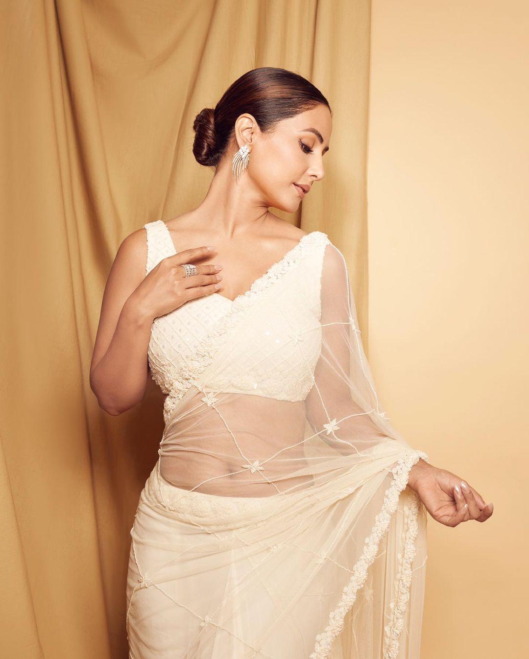 Hina Khan chose a white net saree paired with a matching blouse for her outfit. The actress elegantly tied her hair into a chic bun and opted for neutral makeup