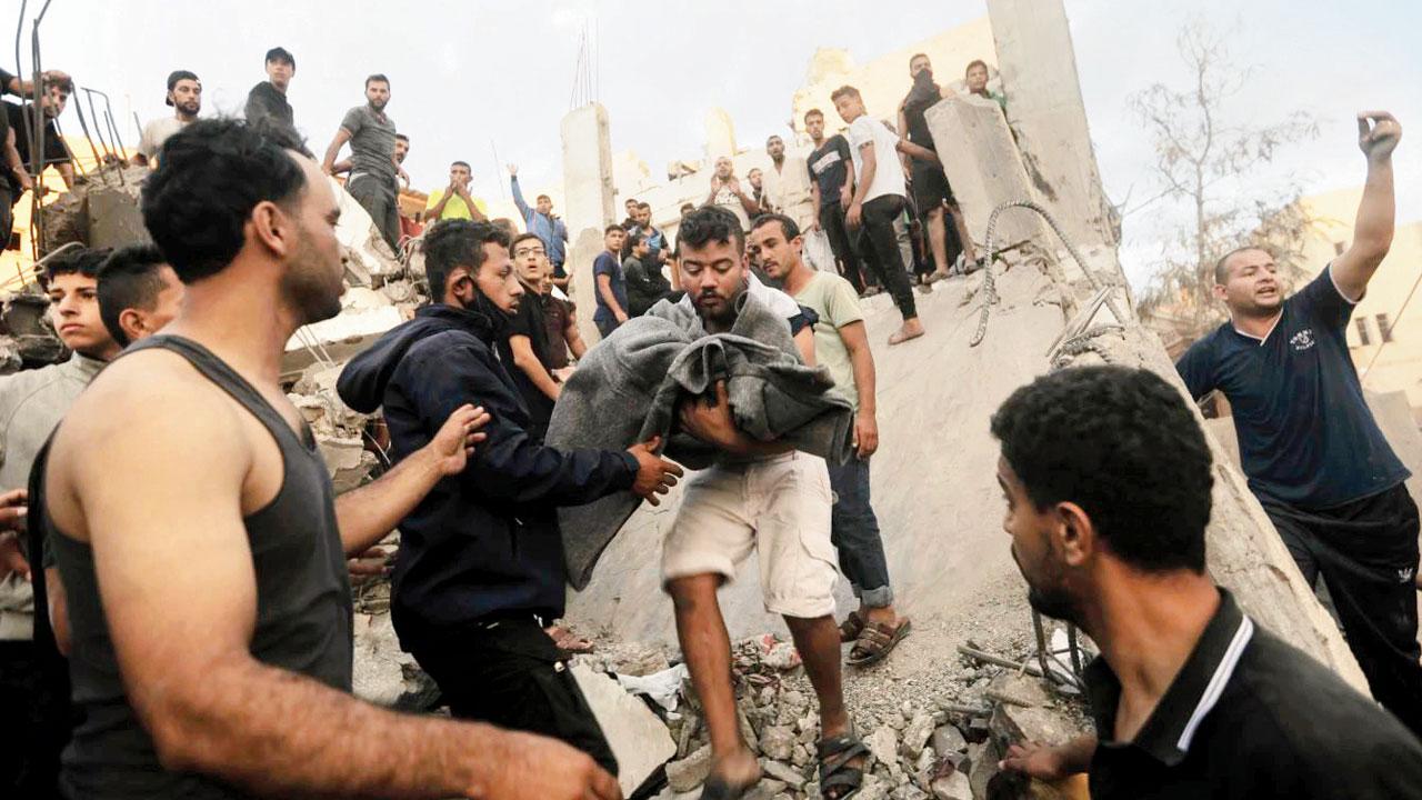 A Palestinian man carries a blanket covering the remains of a person from the rubble of a house. Pic/AP