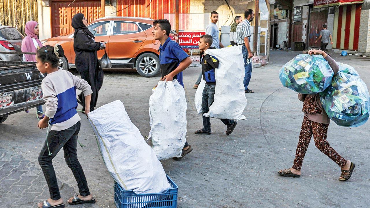 People carry sacks filled with cardboard to use for fire-making