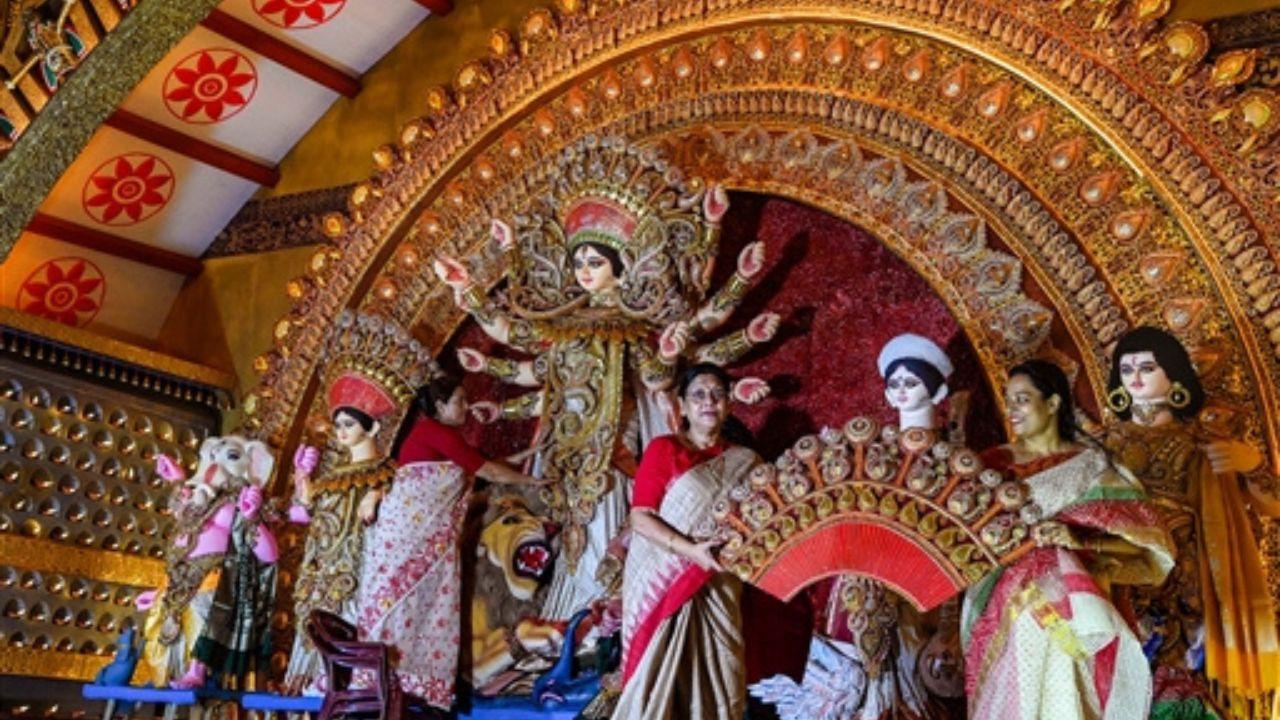 Women members of the community are seen wearing traditional sarees as they participate in decorating the Goddess Durga Puja idol in a community pandal, adding to the cultural richness of the festival.