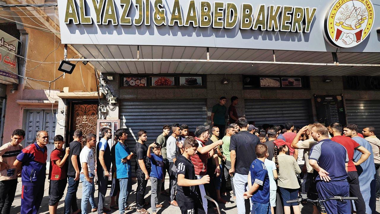 Displaced Palestinians queue for bread. Pics/AP