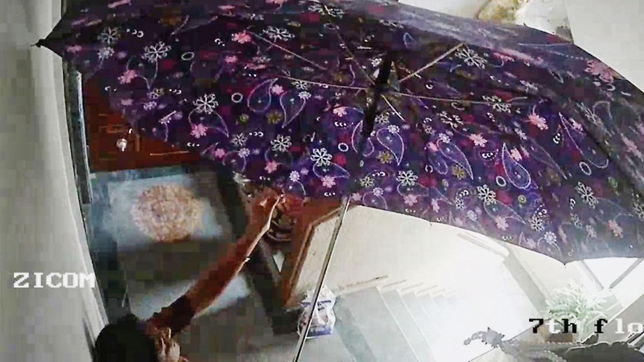 One of the women opens the umbrella in a bid to cover CCTV cameras