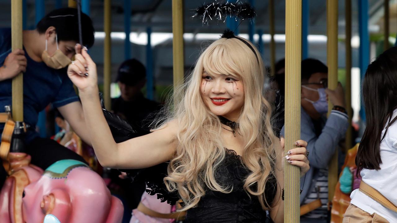 A costumed Taiwanese woman rides a merry-go-round during a Halloween celebrations at Taipei Children's Amusement Park in Taipei, Taiwan.