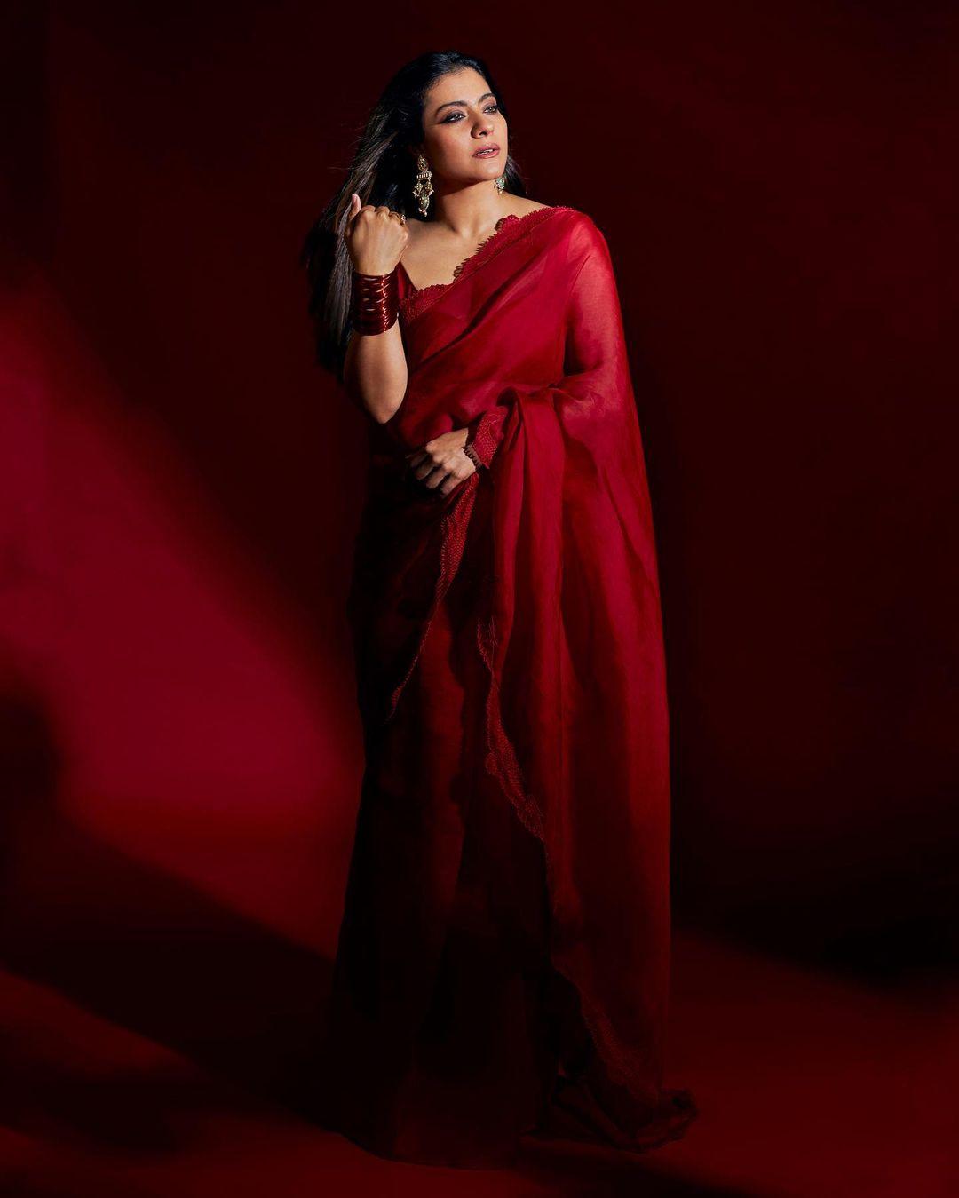 AshtamiOn Ashtami, as the festive excitement hits its peak, this outfit on Kajol makes for the perfect choice. She dons a stunning scarlet red saree, elegantly paired with a sleeveless blouse featuring a delicate scalloped border.