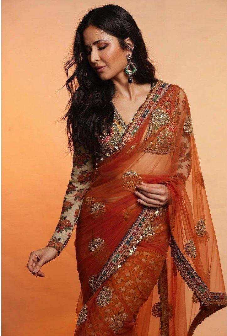 Katrina Kaif made a striking impression in a beautiful orange-toned saree. The saree had a sheer fabric with a patterned layer and was adorned with printed sequin borders. To top it off, her long-sleeved blouse brought an extra touch of style with its distinct combination of prints and understated embellishments, elevating her overall elegant appearance.