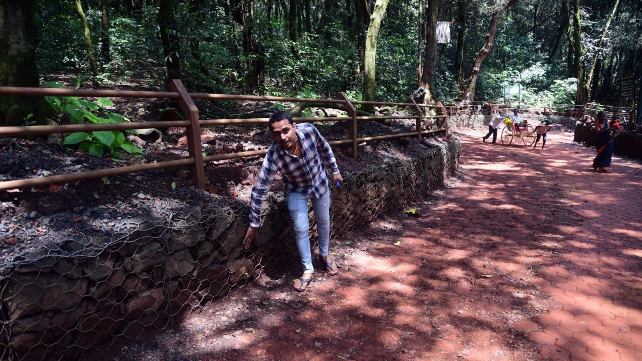 A local shows the gabion metal cage placed on a rock wall along a pathway in Matheran
