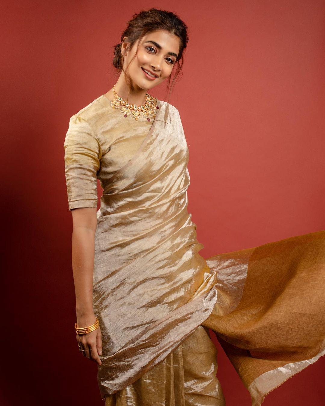 Pooja Hegde looks absolutely stunning in her all-gold linen saree, which she pairs with a stylish half-sleeve blouse. This outfit exudes a sense of luxury, making it a perfect choice for the grand Ashtami celebrations.