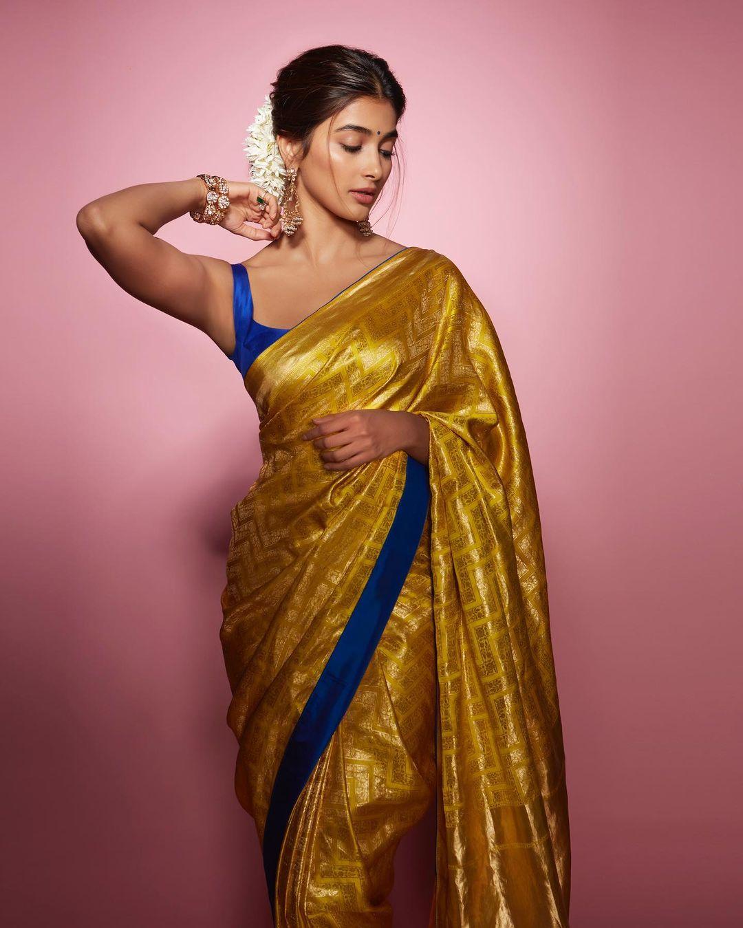 While traditional saris often incorporate classic floral and animal motifs, Hegde's Raw Mango sari showcased zari work in modern chevron patterns, adding a contemporary twist to the traditional style. To create a striking contrast, she paired it with a sleeveless cobalt blue blouse made from the same fabric, which also featured cord piping on the yellow sari.