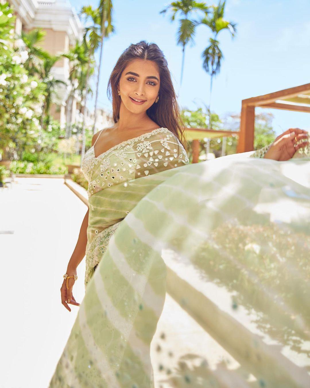 She looked absolutely stunning in a green and white saree, exuding elegance and charm. Her outfit featured subtle mirror work accents, and she paired it with a white strappy blouse that had a stylish plunging neckline. 