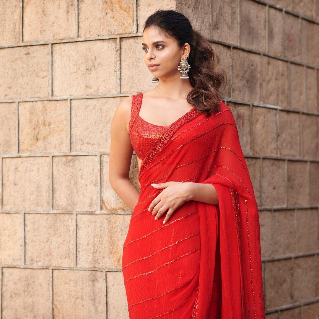 Suhana Khan's fashion choice steals the show in a striking red saree paired with a sleeveless blouse, epitomizing the festive spirit. Her untied hair and signature makeup bring out her natural beauty.