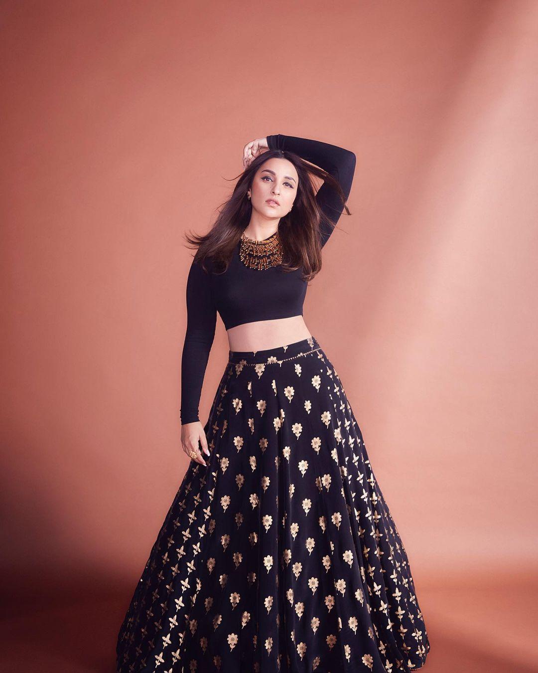 Parineeti Chopra elegantly chose a striking black crop top, skillfully coordinating it with a matching long skirt adorned with exquisite golden embroidery. The actress's fusion of Indo-Western style embodies sheer beauty