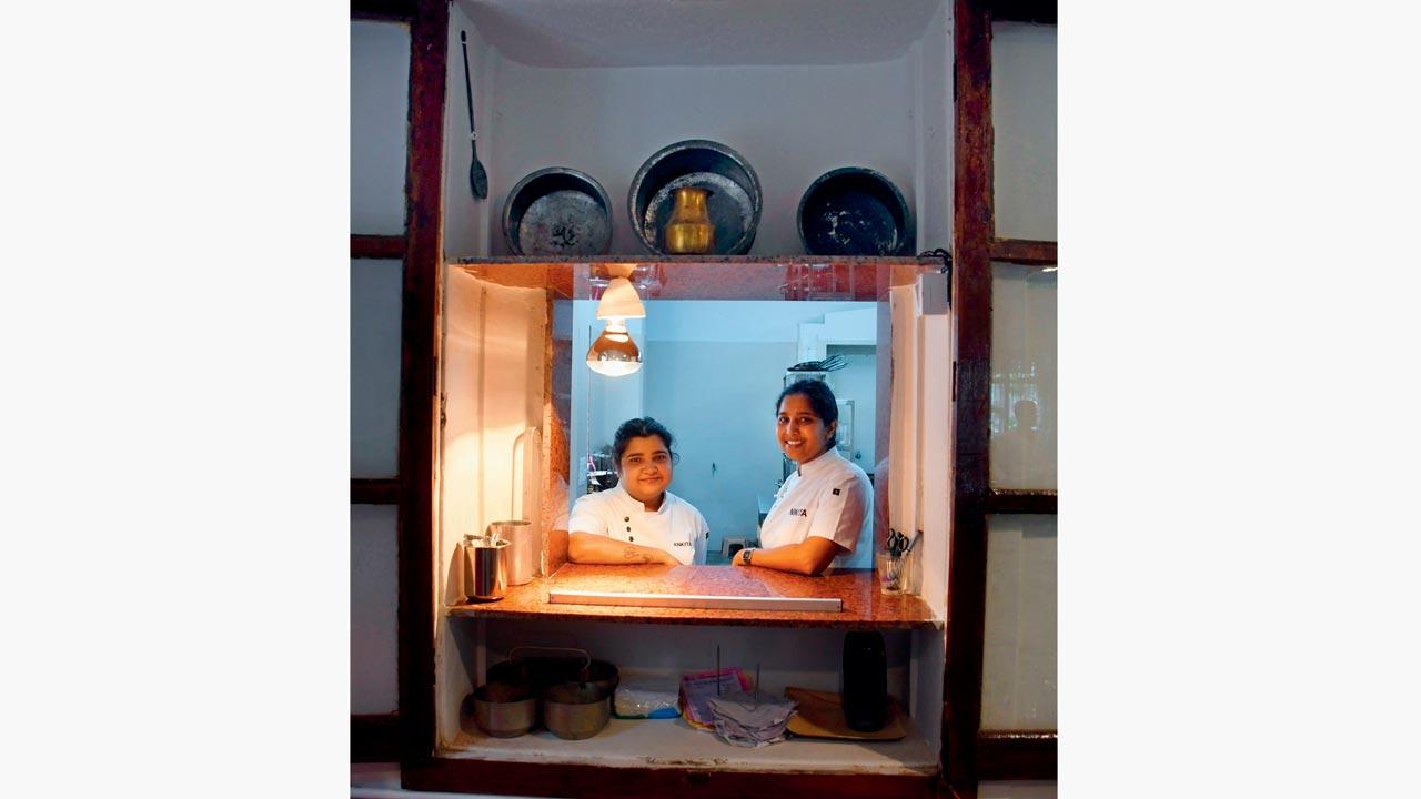 Chefs Nikita and Ankita peek through the window that provides access to the kitchen. The duo has worked in restaurants all over the world before becoming part of Gazra  