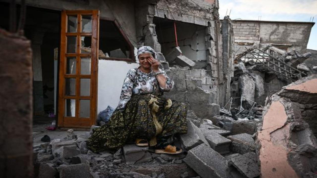 A survivor of the deadly 6.8 magnitude September 8 earthquake cries as she sits on the rubble of her damaged house, in the mountain village of Moulay Brahim in al-Haouz province in central Morocco.