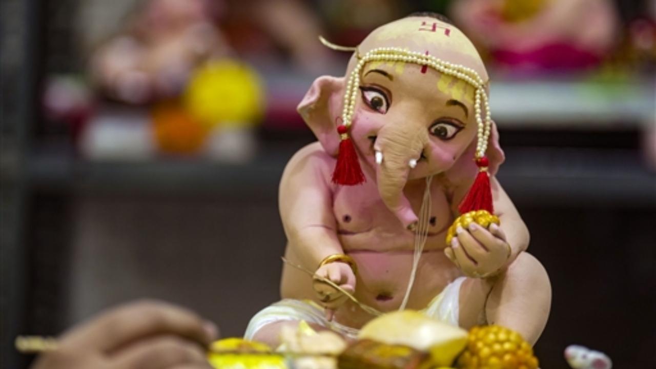 An artist gives final touches to a clay idol of Lord Ganesha ahead of Ganeshotsav