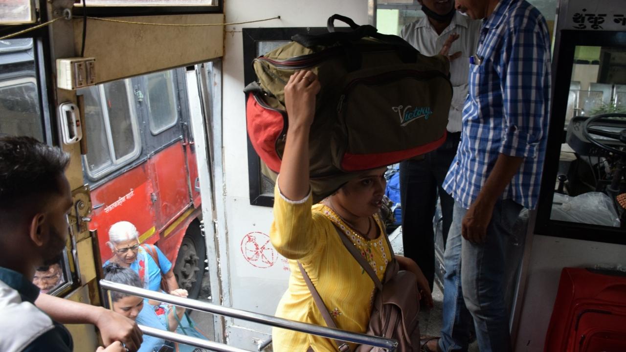 A woman carries her luggage in order to board the state ST bus from the Parel area. Many devotees travel to their native places during the festival season