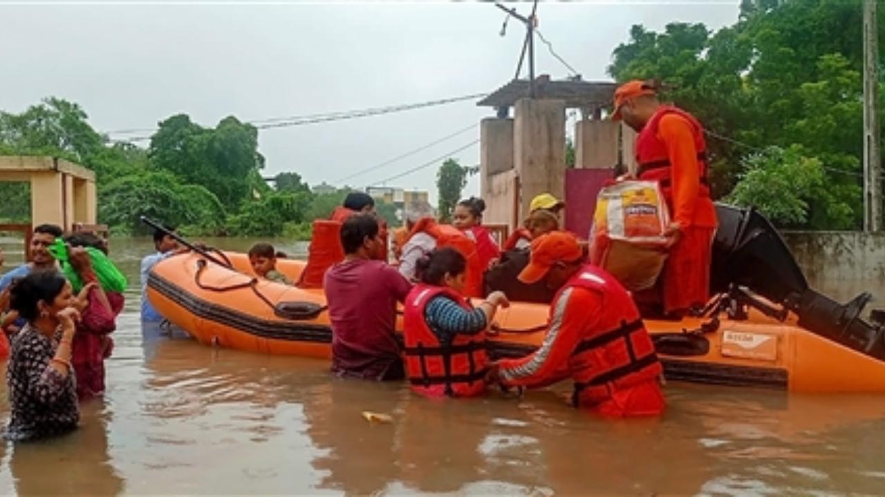 NDRF personnel rescue residents from a flooded area after heavy rains, in Aravalli district