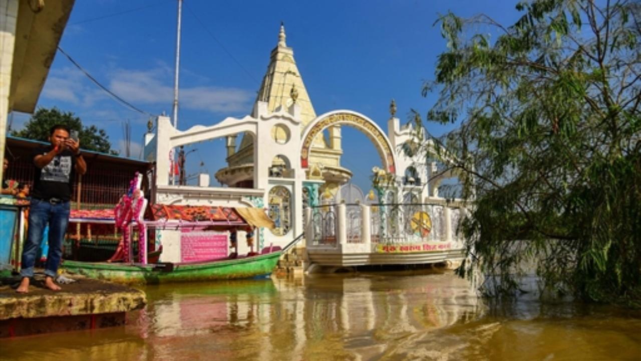 A man takes photographs at a flood-affected area after opening of the Bargi dam gate of the River Narmada at Gwarighat