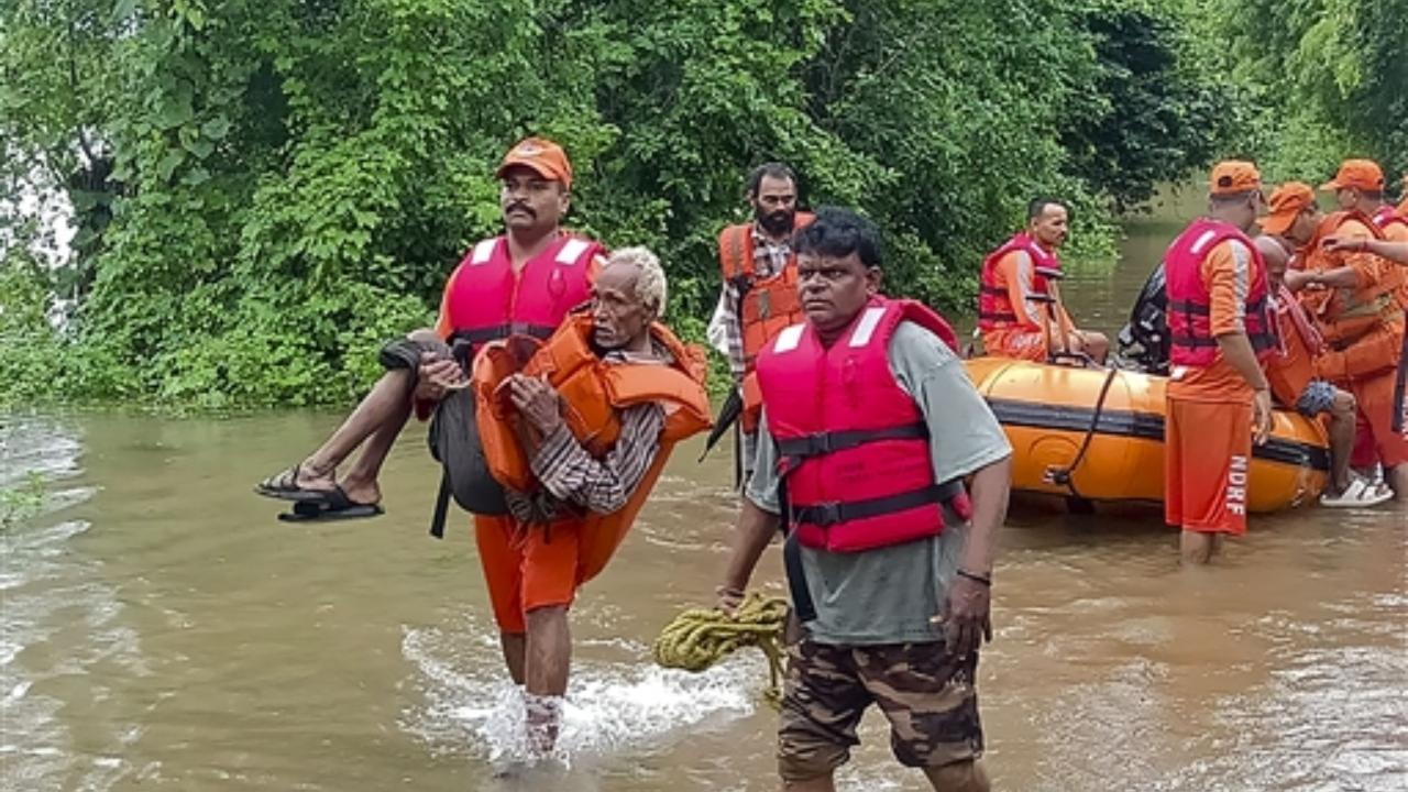 NDRF personnel rescue residents from a flooded area after heavy rains, in Narmada district