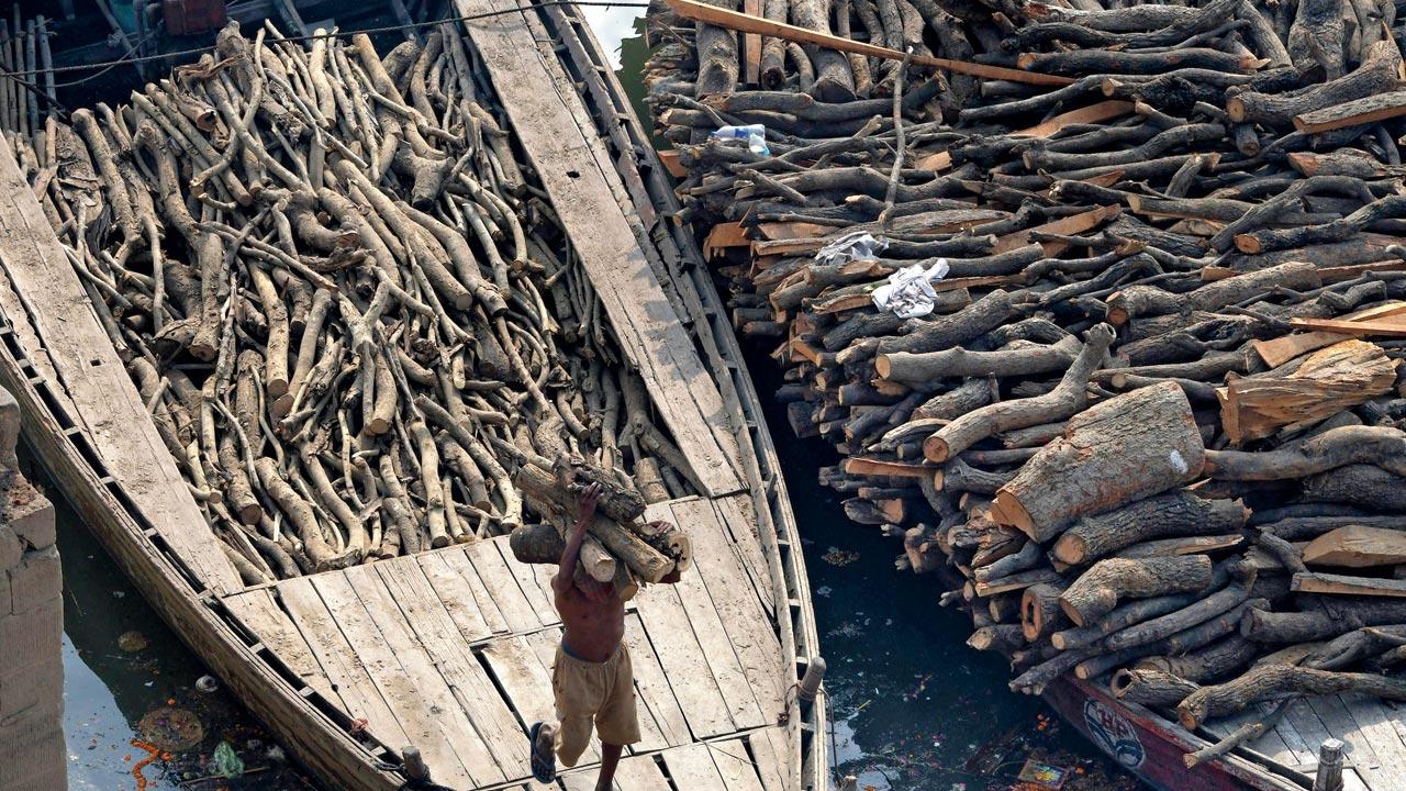 A man is seen unloading wood from a boat to be used at the crematorium grounds in Varanasi. Boys from the Dom community are often sent by mothers to procure firewood from the pyres for their choolahs; the boys “pull out the burnt logs of wood... and drown them in water for a few minutes” before walking back home with the bundle 