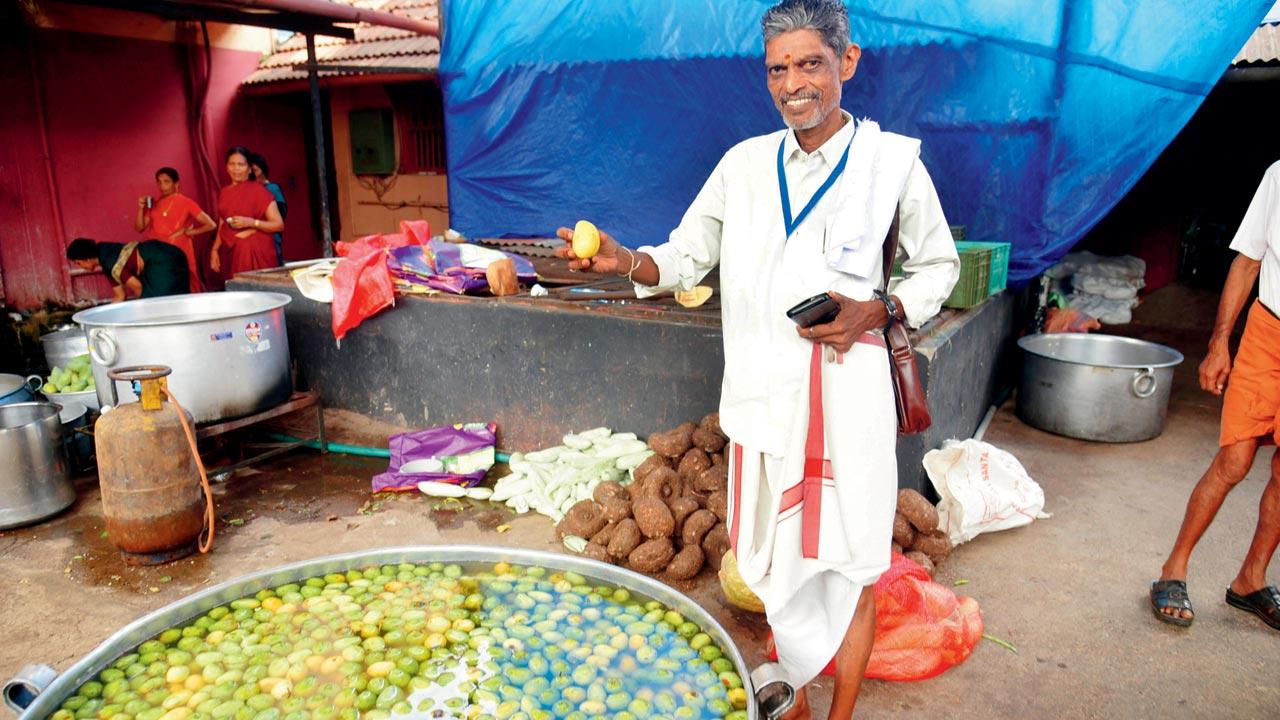P V Subramanyan, food committee convenor of the Paramekkavu Bagavathi temple Devosam holds a mango used for making mambazha pulissery