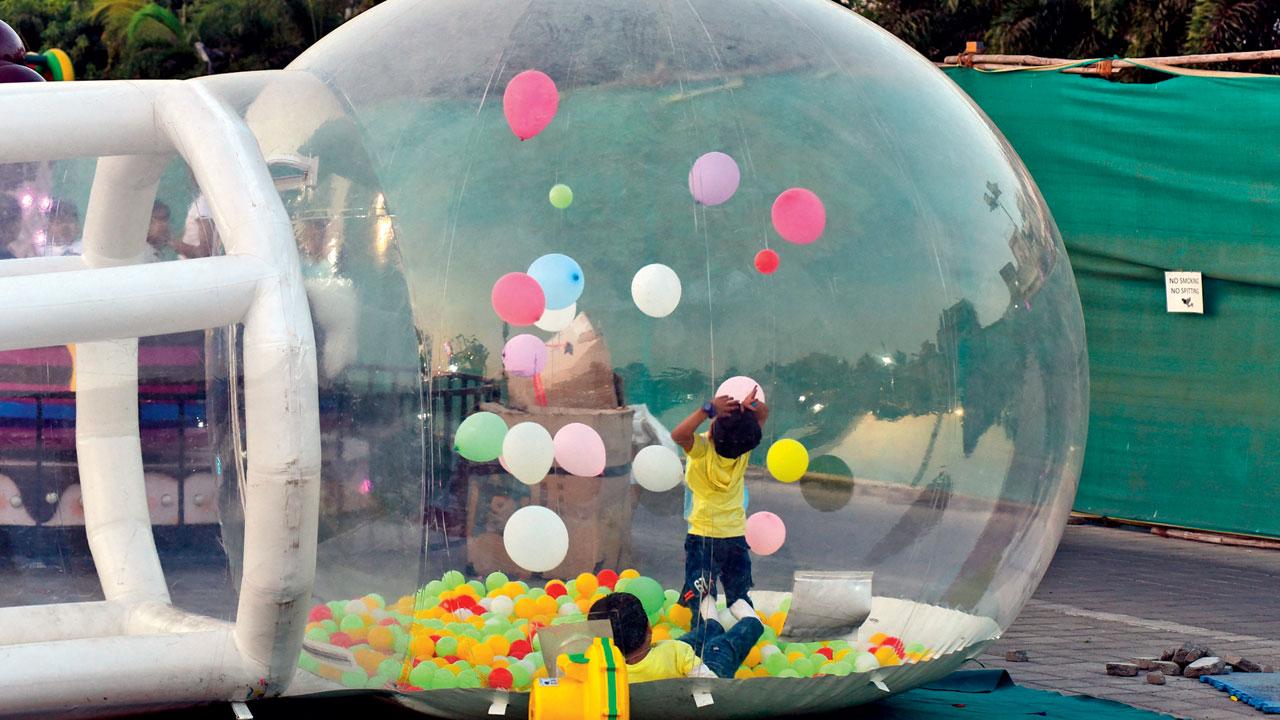 A kid plays with balloons inside the balloon house installation