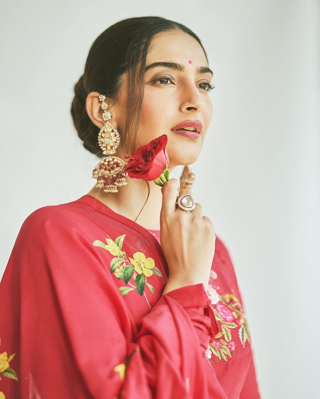 In this look, the actress tied her hair in a chic bun and decorated it with red roses. Further, ditching multiple jewelry pieces, she wore big intricate earrings that added to the beauty of the fit. With striking makeup, Sonam finished her look