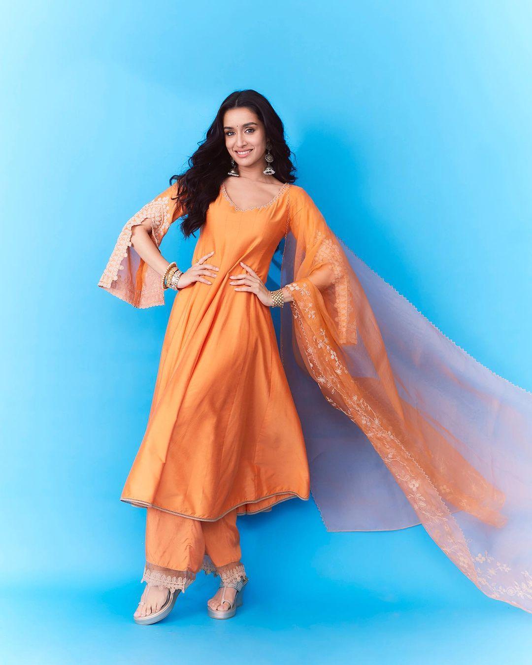 Check out this vibrant look of Shraddha Kapoor, which speaks simplicity and grace. In this look, Shraddha wore a stunning orange suit with fancy sleeves and paired it with matching pants and a sheer dupatta