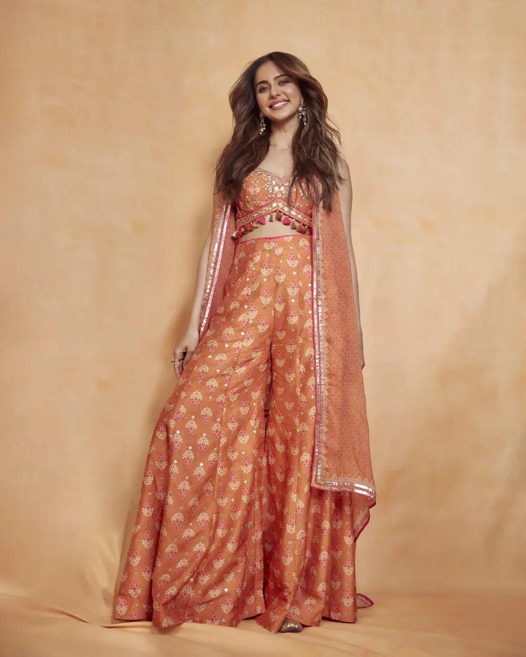 Rakul Preet Singh will be celebrating her first Baisakhi post-marriage. The actress's wardrobe is a perfect place to take inspiration from. In this look, Rakul wore a beautiful orange blouse paired with matching palazzos. The actress put a sheer shrug on it, which made her dress look balanced