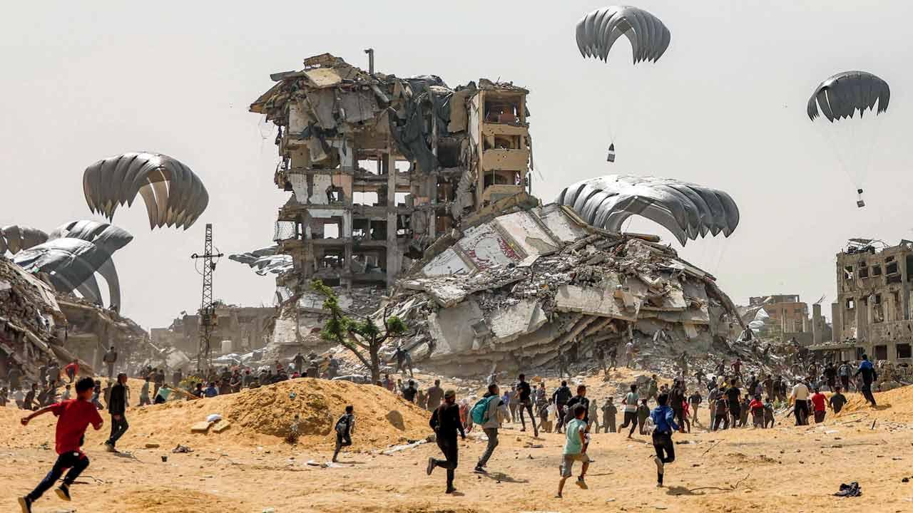 People rush towards landing humanitarian aid packages dropped over northern Gaza Strip on Tuesday. Pic/AFP