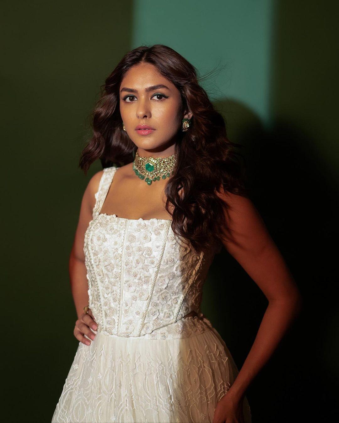 Mrunal accessorized her outfit with an intricate necklace and earrings featuring green gemstones, making a striking contrast