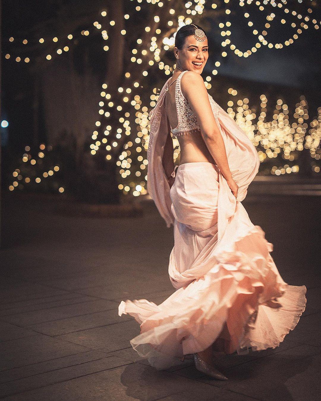 In this stunning appearance, Nia wore a white saree with a touch of pink and paired it with a matching strappy blouse. She tied her hair in a bun and completed her look with a stunning mangtika