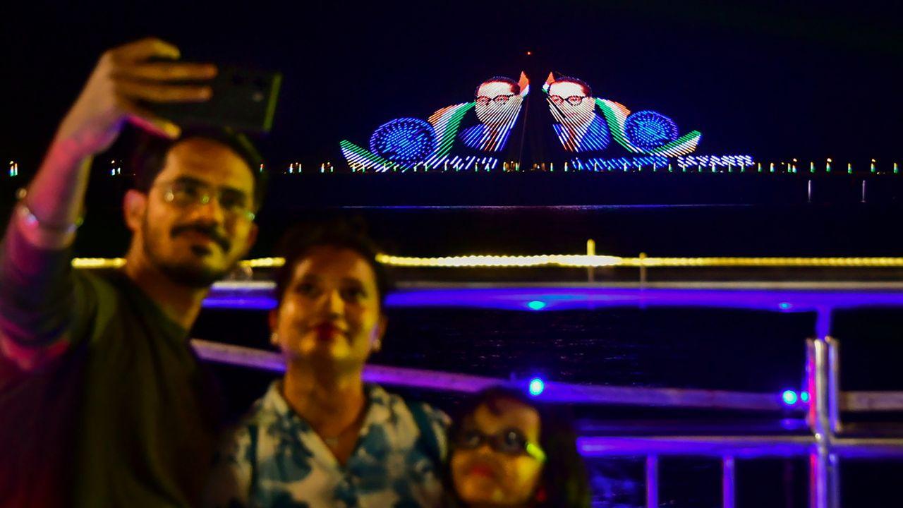 A family takes a selfie against the Bandra - Worli sea link illuminated with digital images of Dr B R Ambedkar ahead of Ambedkar Jayanti, in Mumbai, Saturday, April 13, 2024. (PTI Photo)