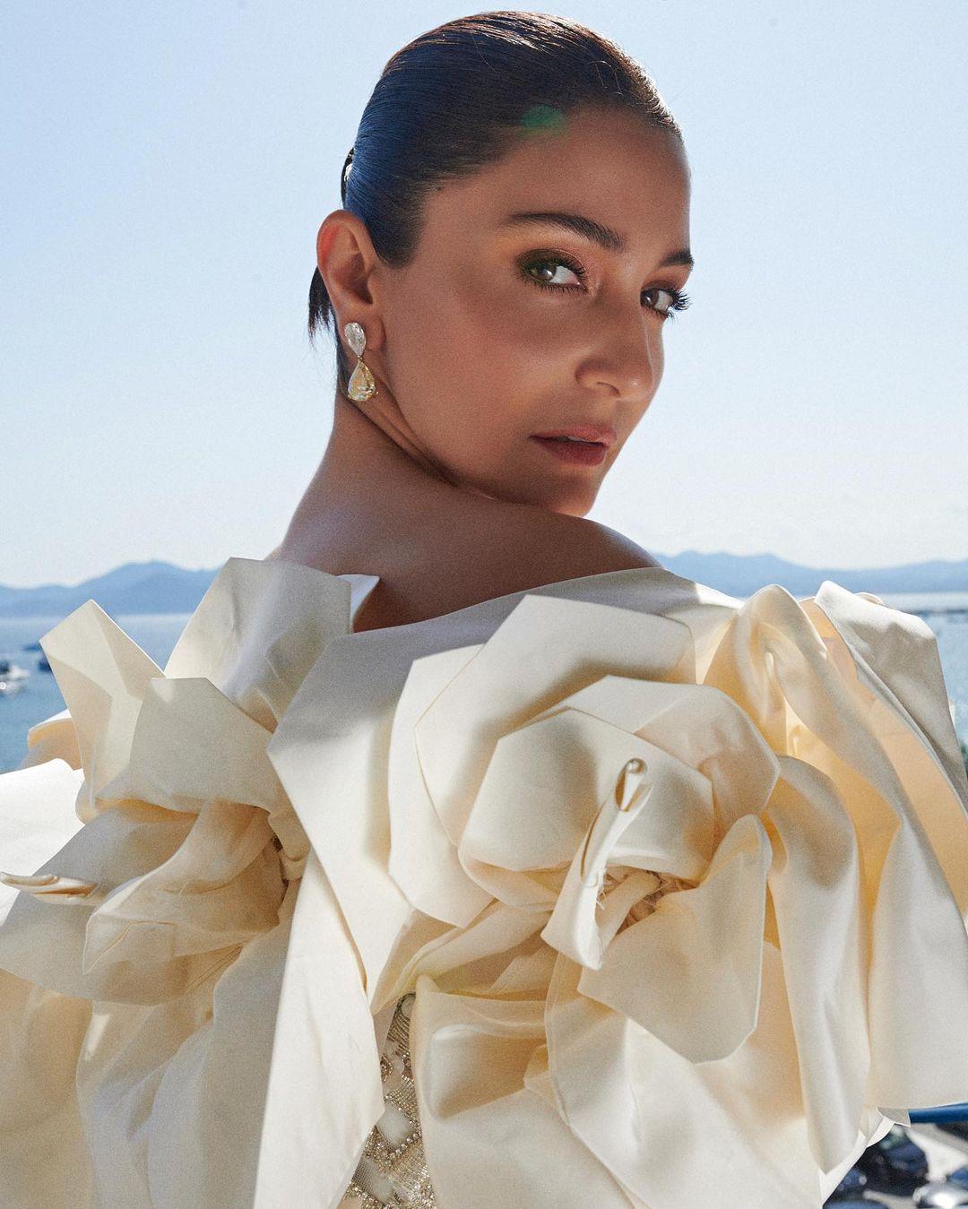 Her hair was styled into a neat updo to draw attention to the 3D flowers on her shoulder. 