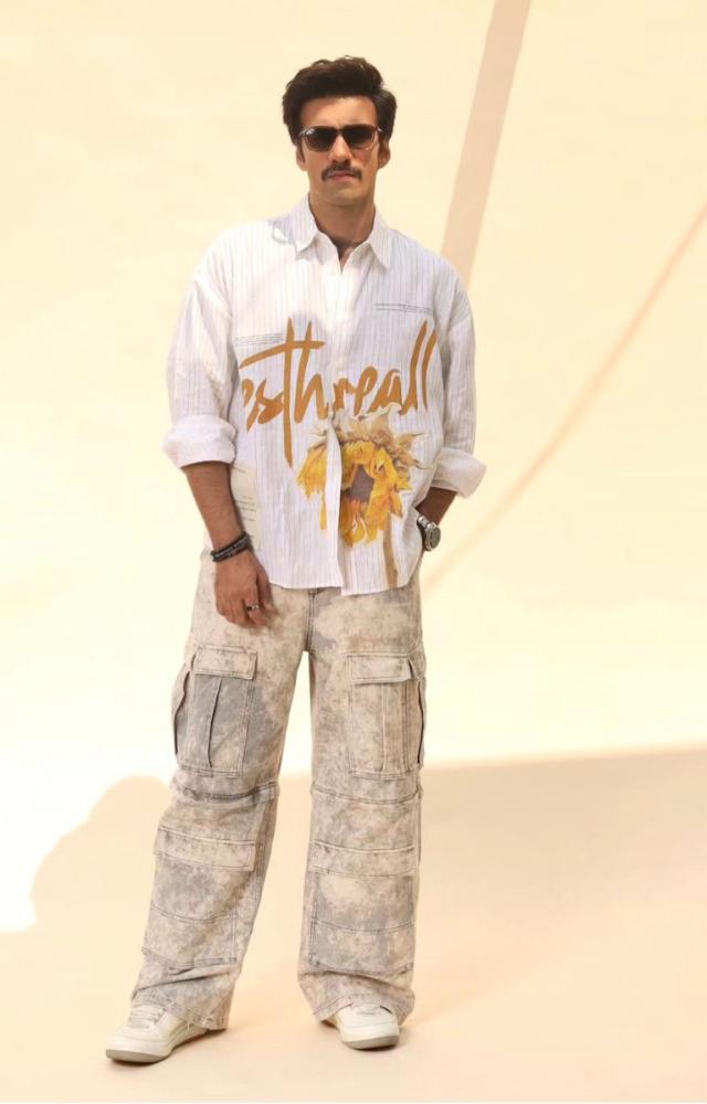 Avinash effortlessly rocks earthy tones with a brown tee layered under a graphic white shirt, paired with baggy cargos and sleek black sunglasses