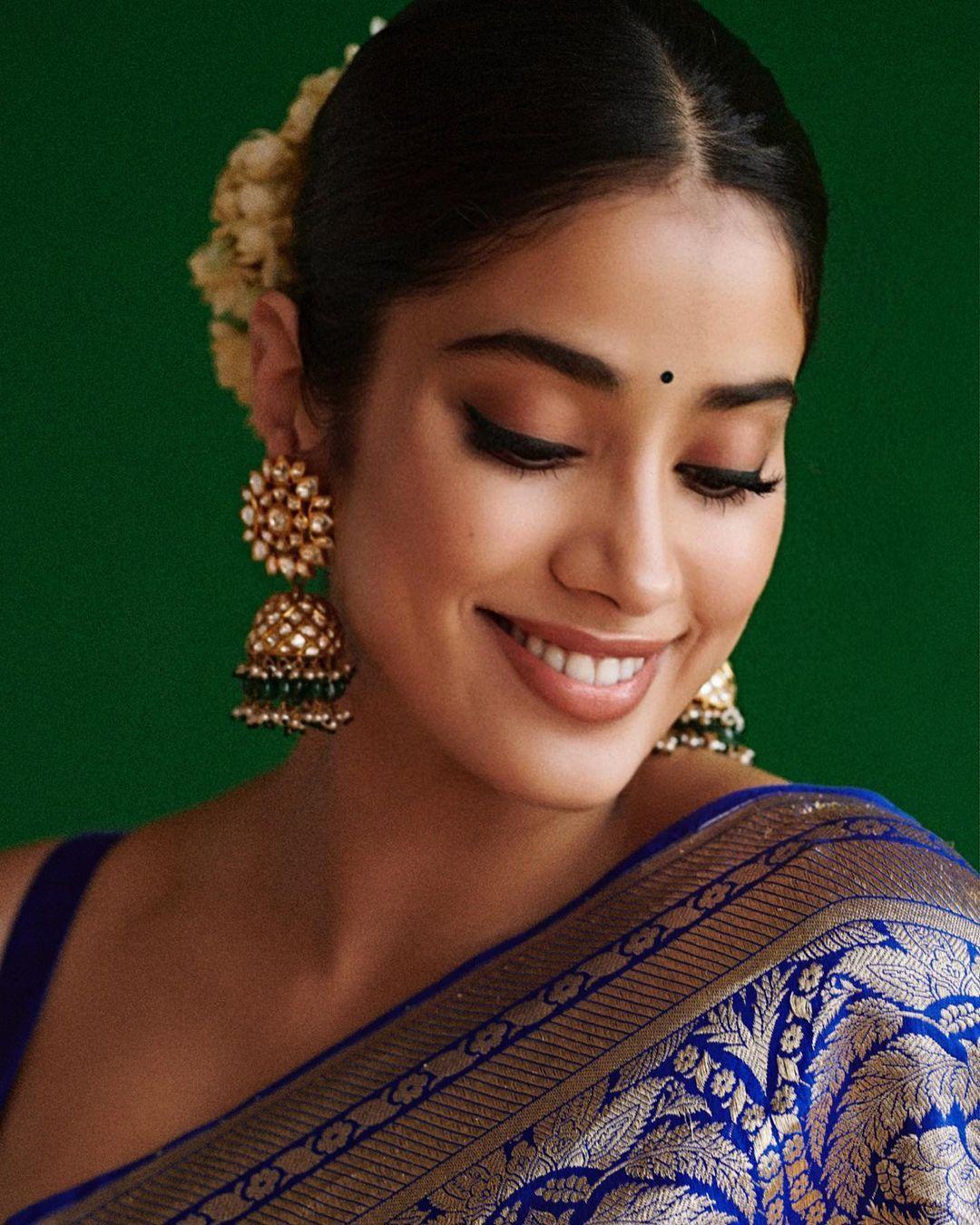 She wears a floral garland in her hair, adding to her elegance. Janhvi complements her saree with bold jhumkas, giving her outfit a traditional yet glamorous vibe.