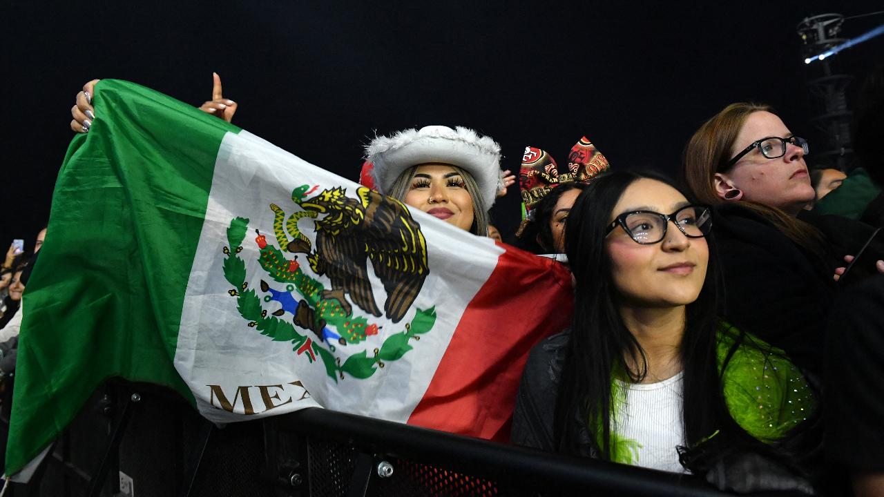 Fans holding a Mexican national flag watch Colombian singer J Balvin perform at the Coachella stage during the Coachella Valley Music and Arts Festival in Indio, California